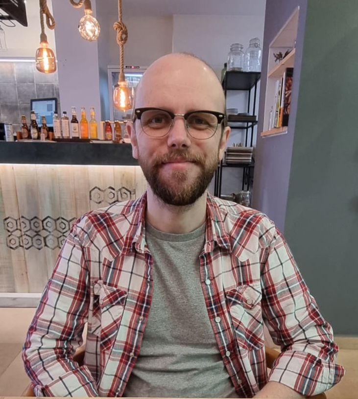 Ian in a raw vegan, Spanish restaurant, wearing a white check shirt and glasses